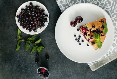 Beyaz bir tabak, peçete üzerinde tatlı için yaban mersini, rasberry, kiraz ve nane ile pasta Parçası. Lezzetli ev yapımı kek parçaları