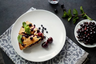 Beyaz bir tabak, peçete tatlı için yaban mersini, rasberry ve nane ile pasta Parçası. Bir arka plan üzerinde lezzetli ev yapımı kek Parçaları