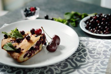 Beyaz bir tabak, peçete üzerinde tatlı için yaban mersini, rasberry, kiraz ve nane ile pasta Parçası. Lezzetli ev yapımı kek parçaları