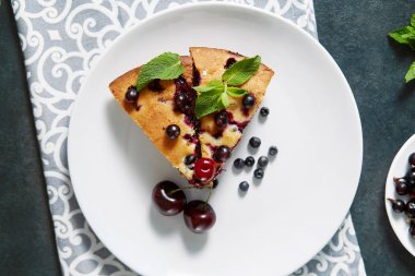 Beyaz bir tabak, peçete tatlı için yaban mersini, rasberry ve nane ile pasta Parçası. Bir arka plan üzerinde lezzetli ev yapımı kek Parçaları