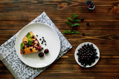 Beyaz bir tabak, peçete üzerinde tatlı için yaban mersini, rasberry, kiraz ve nane ile pasta Parçası. Lezzetli ev yapımı kek parçaları