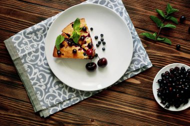 Beyaz bir tabak, peçete tatlı için yaban mersini, rasberry ve nane ile pasta Parçası. Ahşap tahtaarka planda lezzetli ev yapımı kek parçaları