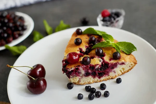 Beyaz bir tabak, peçete üzerinde tatlı için yaban mersini, rasberry, kiraz ve nane ile pasta Parçası. Lezzetli ev yapımı kek parçaları