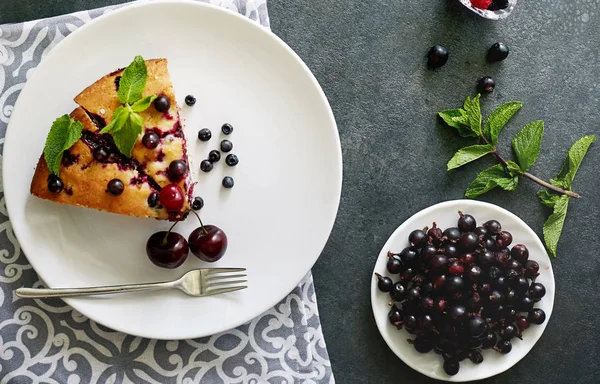 Beyaz bir tabak, peçete tatlı için yaban mersini, rasberry ve nane ile pasta Parçası. Bir arka plan üzerinde lezzetli ev yapımı kek Parçaları