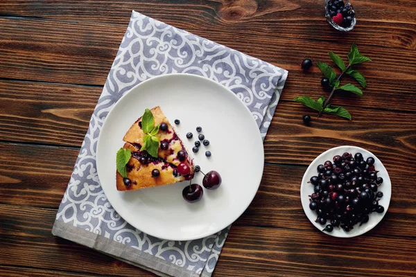 Beyaz bir tabak, peçete tatlı için yaban mersini, rasberry ve nane ile pasta Parçası. Ahşap tahtaarka planda lezzetli ev yapımı kek parçaları