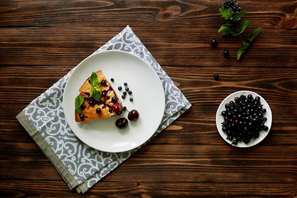 Beyaz bir tabak, peçete tatlı için yaban mersini, rasberry ve nane ile pasta Parçası. Ahşap tahtaarka planda lezzetli ev yapımı kek parçaları