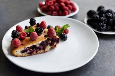 Beyaz bir tabak, peçete tatlı için yaban mersini, rasberry ve nane ile pasta Parçası. Bir arka plan üzerinde lezzetli ev yapımı kek Parçaları