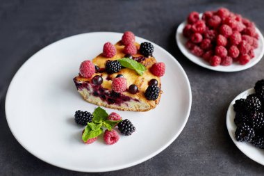 Beyaz bir tabak, peçete tatlı için yaban mersini, rasberry ve nane ile pasta Parçası. Bir arka plan üzerinde lezzetli ev yapımı kek Parçaları