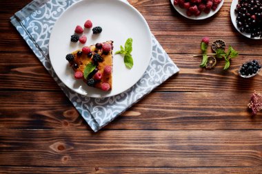Beyaz bir tabak, peçete tatlı için yaban mersini, rasberry ve nane ile pasta Parçası. Ahşap tahtaarka planda lezzetli ev yapımı kek parçaları