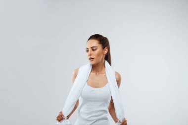 Sağlıklı, güzel sporcu kadınlar havluyla eşofman giyerler ve gri arka planda izole görünürler.