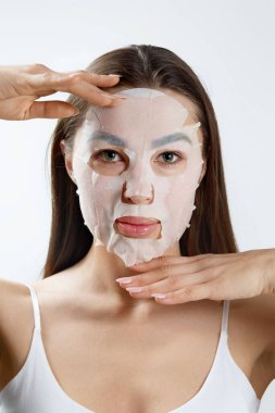 Güzellik Maskesi. Yüzüne nemlendirici maske takmış güzel bir genç kadın. Kozmetik spa maskesi. Yüz tedavisi