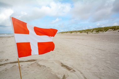 Danish flag in the wind at sand beach near Blavand, Jutland Denmark clipart