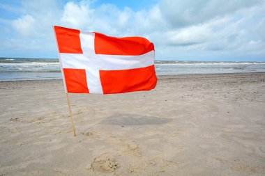 Danish flag in the wind at sand beach near Blavand, Jutland Denmark clipart
