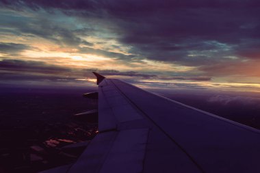 bangkok gün batımında karanlık yağmur bulutları üzerinde uçan uçağın kanat