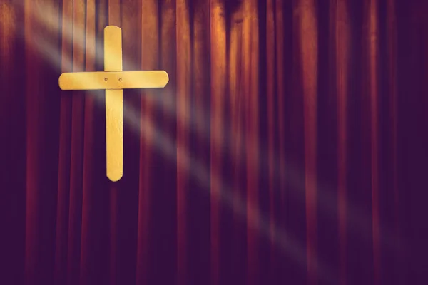 Croce di legno giallo su sfondo tenda marrone scuro in piccola chiesa con raggio di luce — Foto Stock