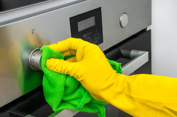El olarak eldiven yeşil bez ile fırın mutfak - ev işleri ve temizlik kavramını silerek