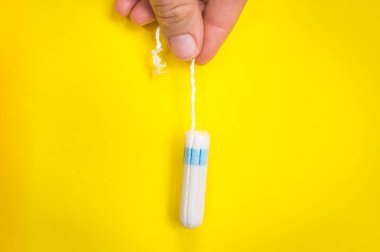 Kadın adet tampon sarı arka plan - adet hijyen kavramı üzerinde elinde tutuyor