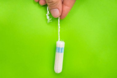 Kadın adet tampon yeşil arka plan - adet hijyen kavramı üzerinde elinde tutuyor