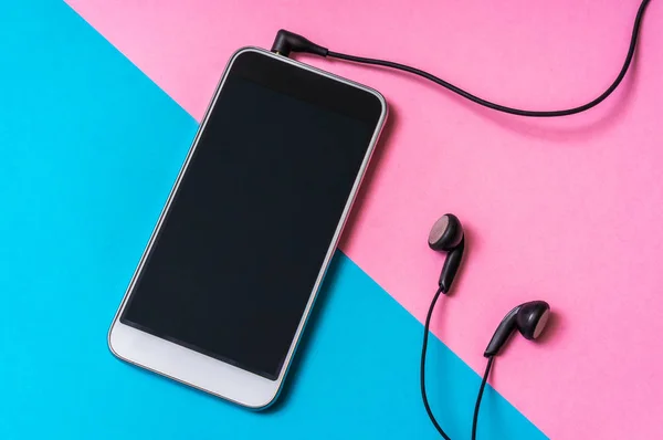 Mobile phone with headphones isolated on colorful background - close-up view