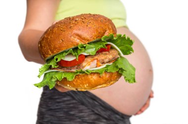 Göbek ile hamile kadın bir burger - gebelik kavramında yeme sağlıksız tutuyor