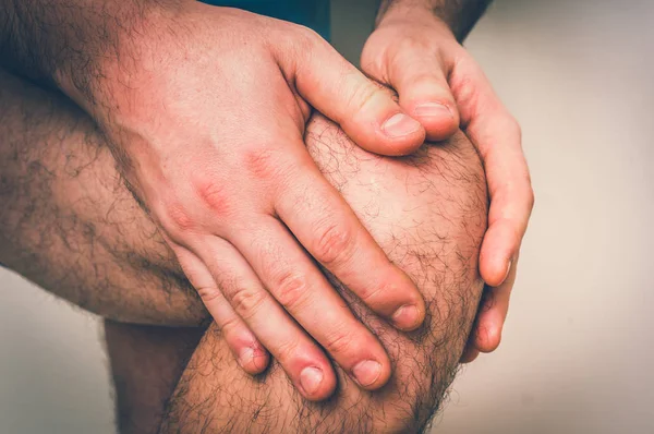 膝盖疼痛的男人抱着他疼痛的腿 身体疼痛概念 复古风格 — 图库照片