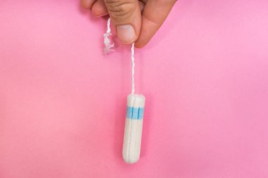 Kadın adet tampon pembe arka plan - adet hijyen kavramı üzerinde elinde tutuyor