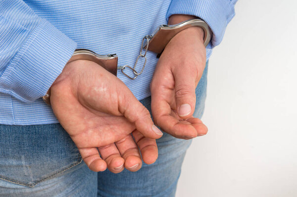 Арестованная женщина в наручниках с руками за спиной - изолированы на белом фоне
