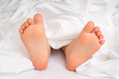 Küçük bebek ayaklar altında beyaz battaniye yatakta