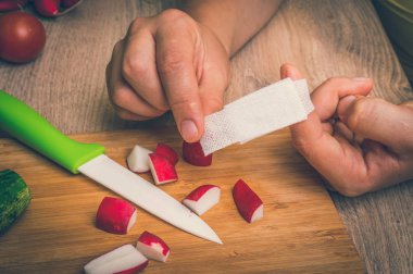 Kadın onun parmak - mutfakta yaralanma - retro tarzı grup yardım sıva uyguluyor