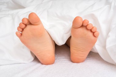 Küçük bebek ayaklar altında beyaz battaniye yatakta