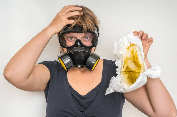 Mother with gas mask changing smelly diaper - baby care concept