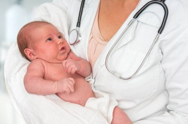 Çocuk doktoru Doktor stetoskop ile yeni doğan bebek kollarında tutuyor