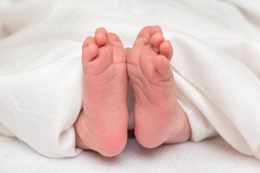 Yeni doğan bebek ayak beyaz battaniye altında yatakta