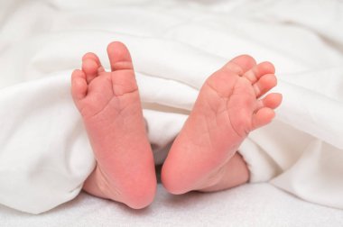 Yeni doğan bebek ayak beyaz battaniye altında yatakta