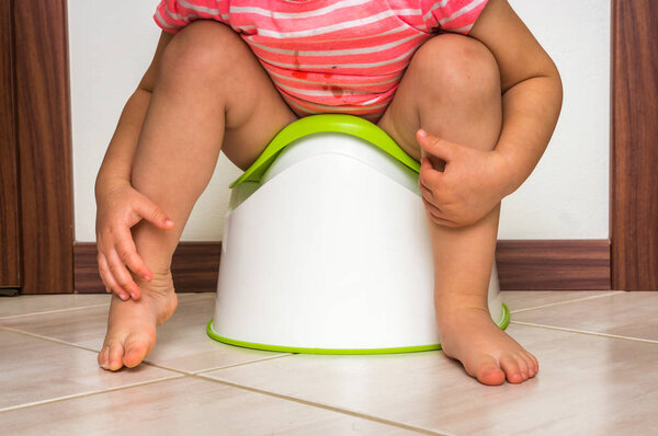 Child is sitting on baby potty - toilet training concept