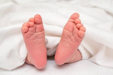 Yeni doğan bebek ayak beyaz battaniye altında yatakta