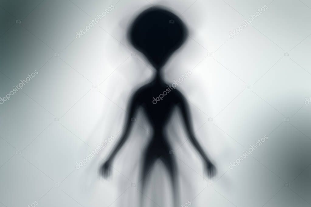 Silhouette of spooky alien and bright light on behind him - UFO concept