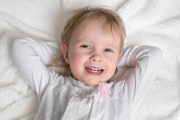 Feliz Niño Sonriente Está Acostado Sobre Una Manta Blanca — Foto de Stock