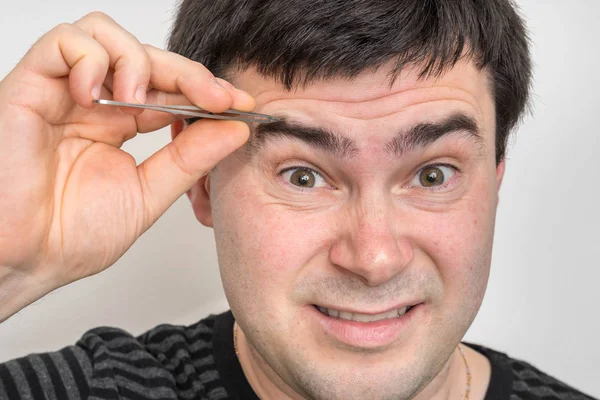 Joven Hombre Está Arrancando Cejas Con Pinzas — Foto de Stock