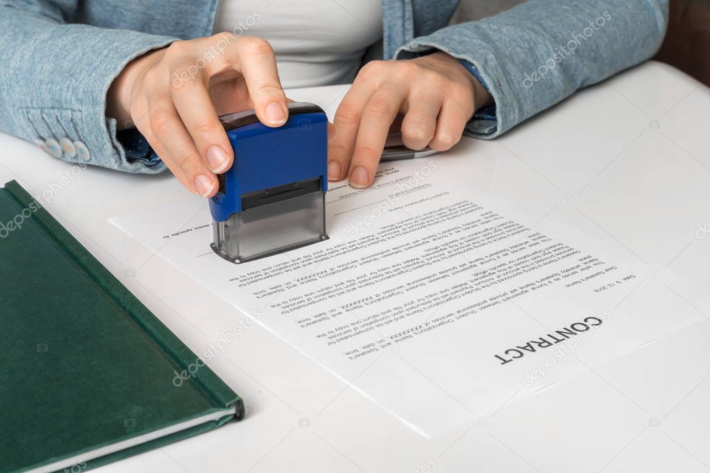 Business woman putting stamp on documents in the office - signing contract concept