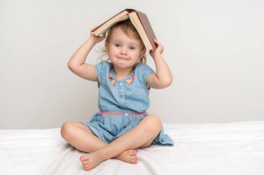 Sevimli küçük çocuk mavi elbiseli bir kitap okuma