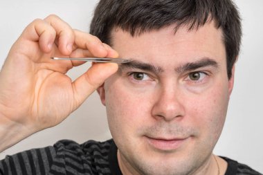 Adam kaşlarını cımbızla koparma
