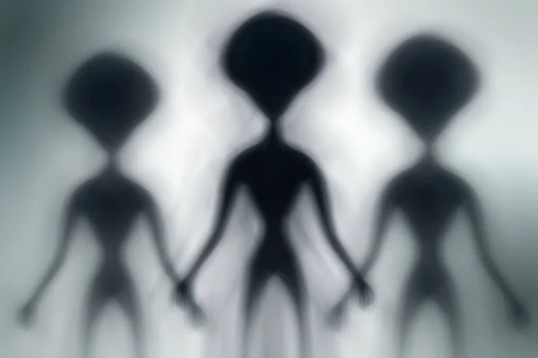 Silhouettes of spooky aliens and bright light on behind them — Stock Photo, Image