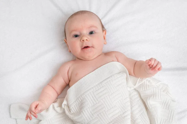 Newborn baby is lying on back on white blanket — Stock Photo, Image