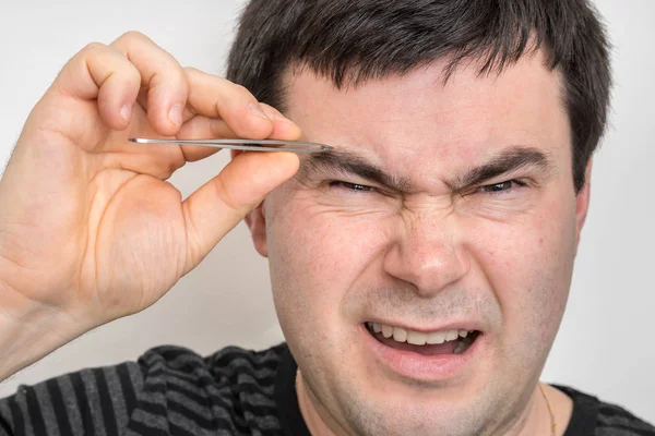 El hombre está arrancando las cejas con pinzas — Foto de Stock