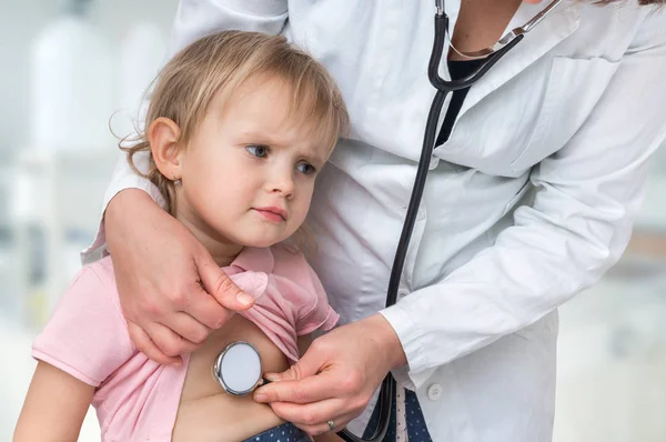 Médico pediatra examinando a una niña por estetoscopio —  Fotos de Stock