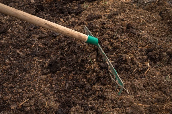 Travailleur avec râteau préparation du sol pour la plantation - concept de jardinage — Photo