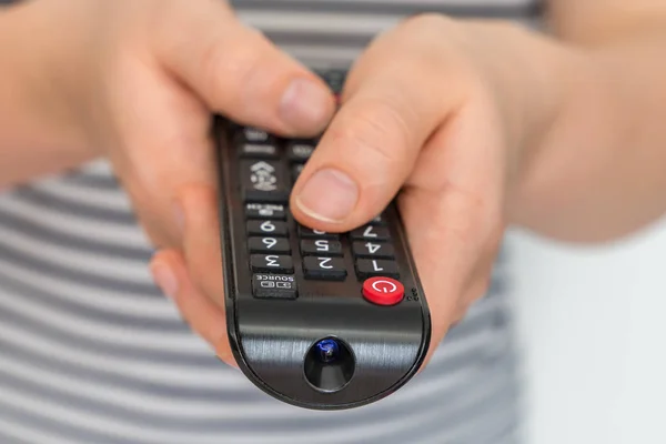 Controle remoto em mãos femininas apontando para TV — Fotografia de Stock