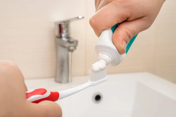 Extrusion of toothpaste on the brush in the bathroom — Stock Photo, Image