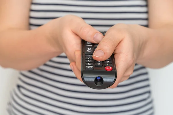 Remote control in female hands pointing to TV Stock Photo